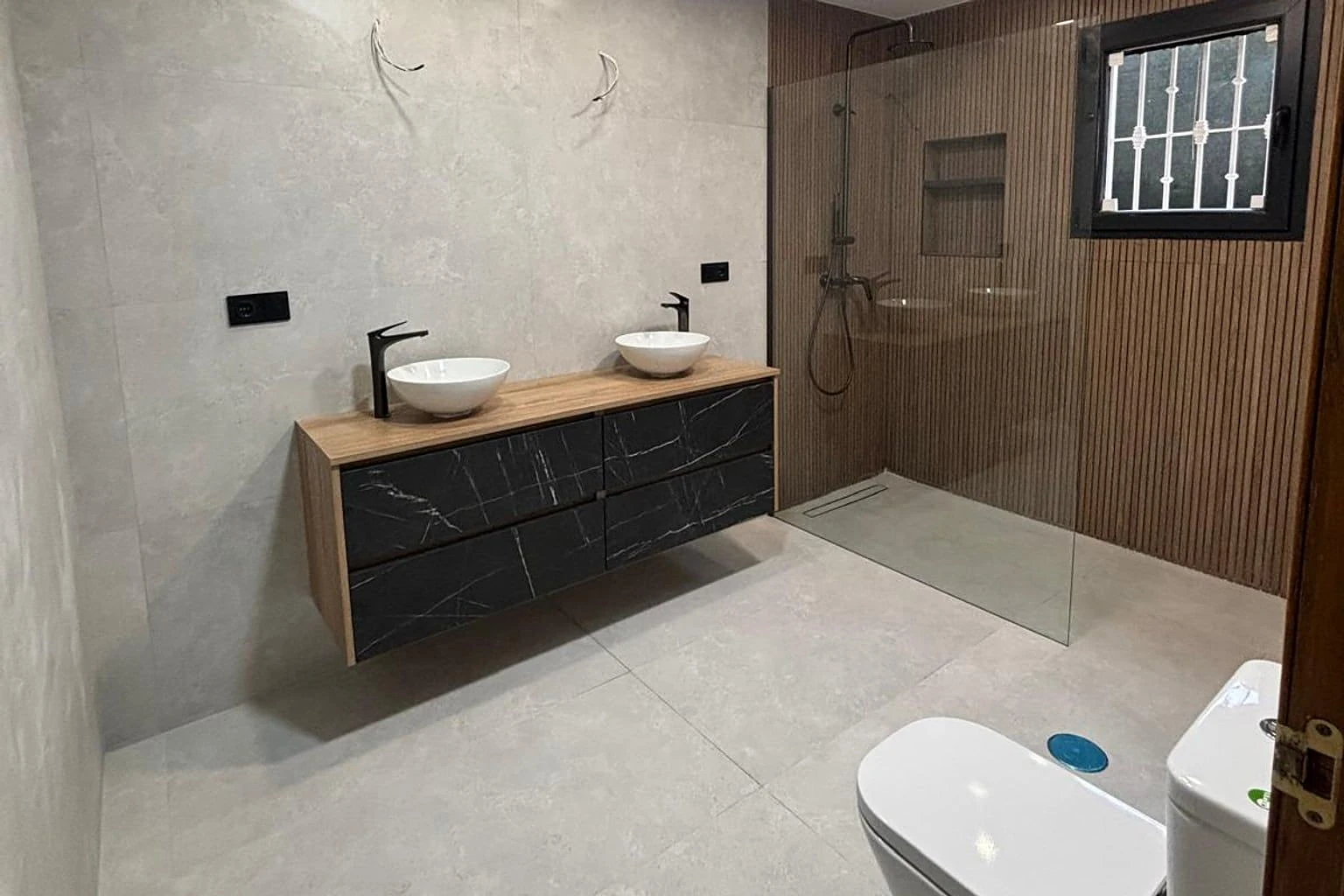 Baño reformado con doble lavabo y ducha de obra