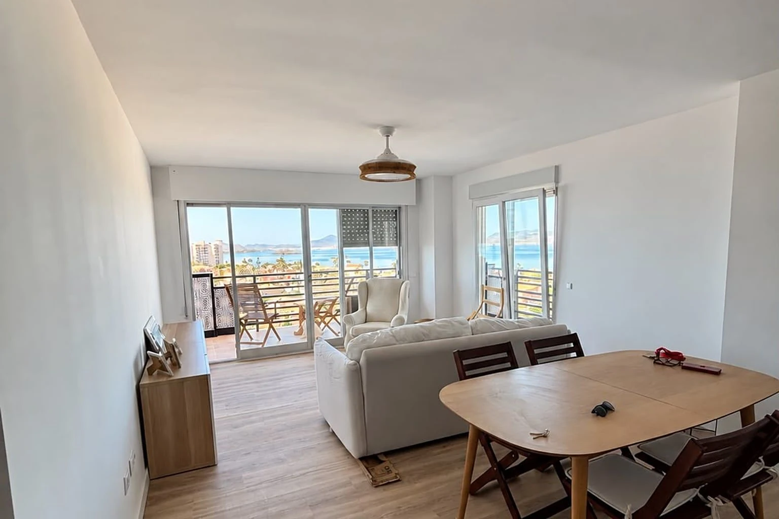 Salón reformado por Grupo Reformz con suelo de madera y vistas al mar en Cartagena